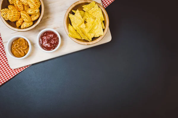 Burgonya chips és snackeket, fekete pala asztalon, felülnézet — Stock Fotó