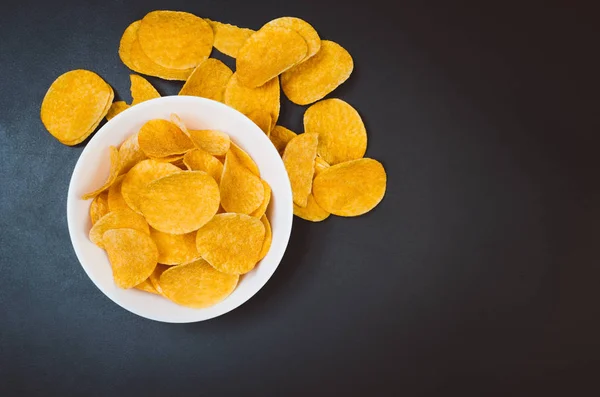 Batatas fritas e lanches na mesa de ardósia preta, vista superior — Fotografia de Stock