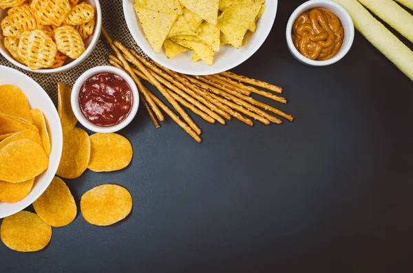 Burgonya chips és snackeket, fekete pala asztalon, felülnézet — Stock Fotó