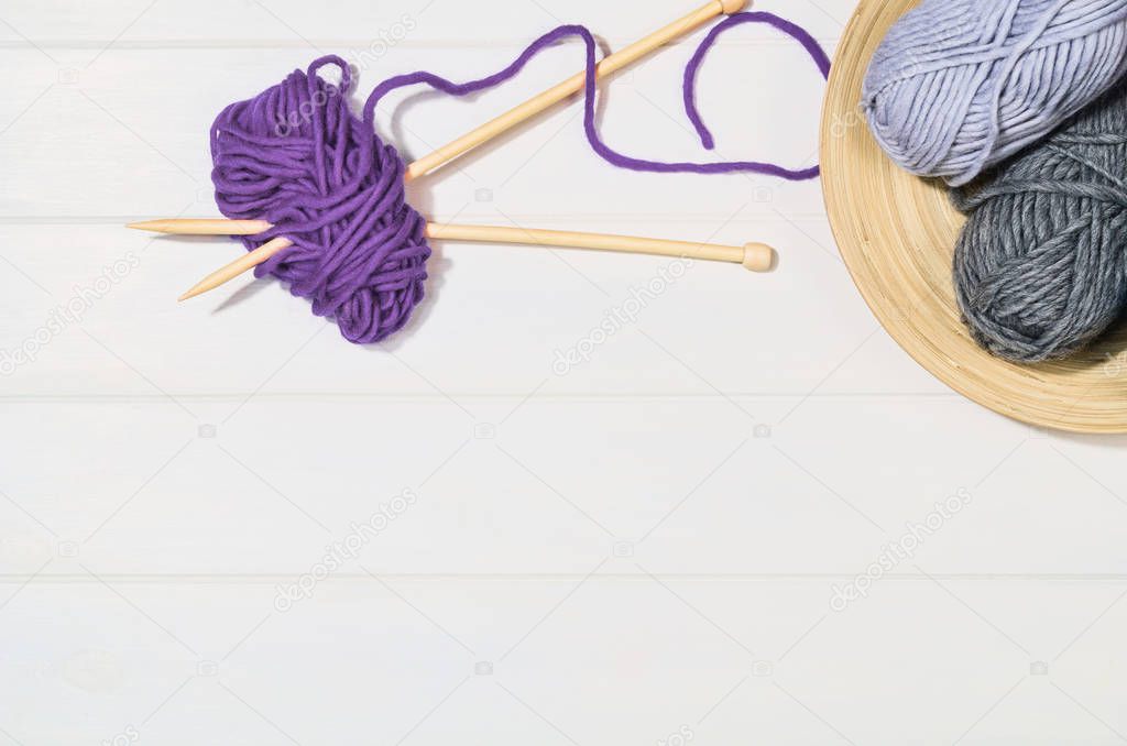 Knitting accessories top view on white wooden background