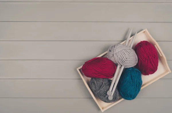 Fond tricoté avec laine et aiguilles sur table en bois gris — Photo