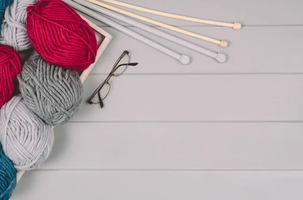 Fond tricoté avec laine et aiguilles sur table en bois gris — Photo