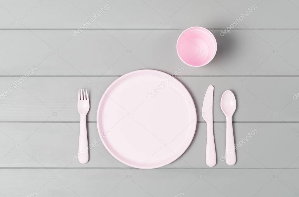 Kids pastel plastic tableware isolated on gray background. Top view