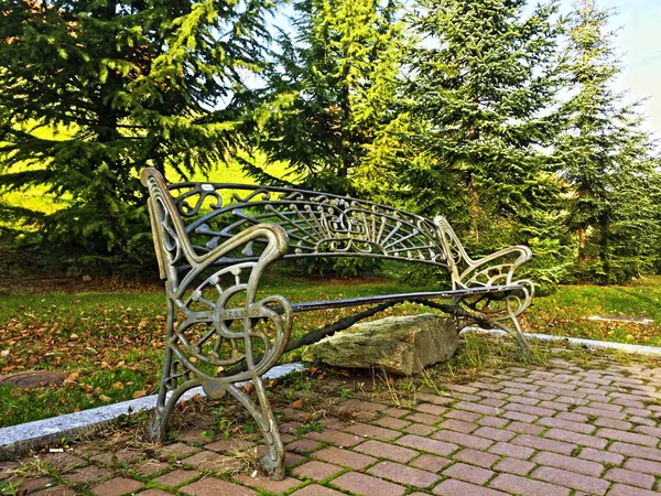 Um banco de ferro em um parque no outono — Fotografia de Stock