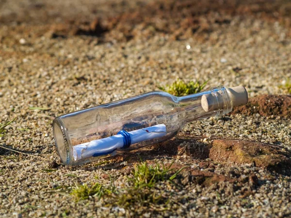 Mensagem em uma garrafa de cristal na praia com água e areia — Fotografia de Stock