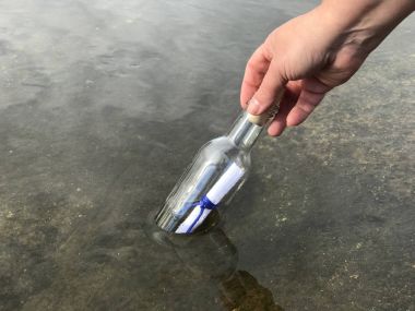 Kristal şişede mesajı olan bir kişi