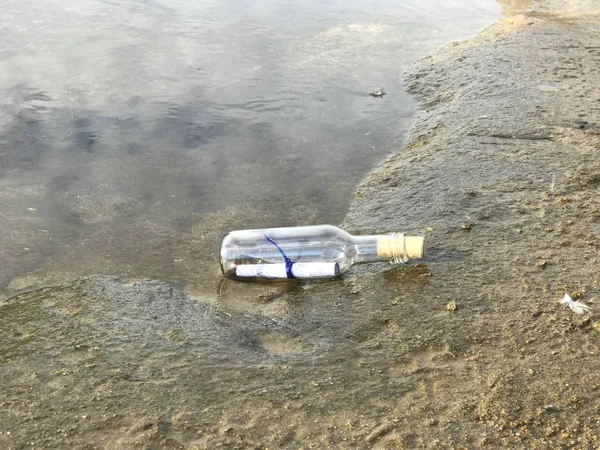 Botschaft in einer Kristallflasche am Strand mit Wasser und Sand — Stockfoto