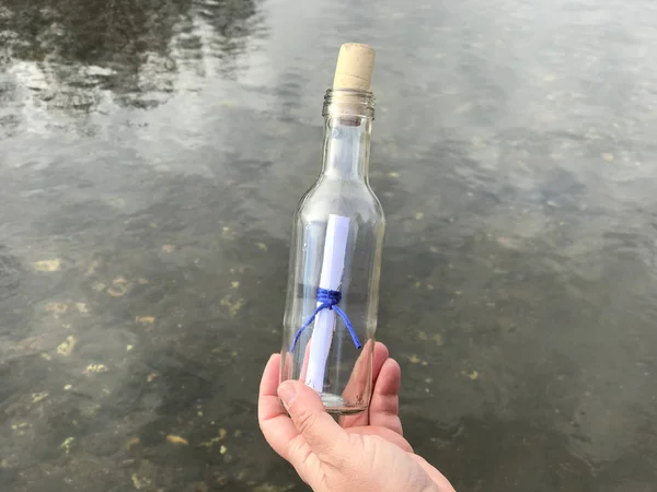 Una persona con un mensaje en una botella de cristal —  Fotos de Stock