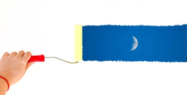 Una persona pintando la luna en una pared blanca con un cepillo de rodillo — Foto de Stock