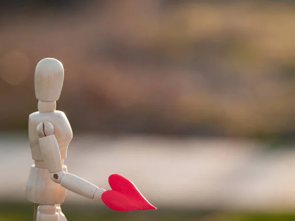 Деревянный манекен с красным сердцем на руках Концепция романтизма и любви — стоковое фото