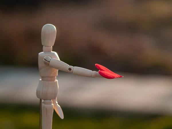 Mannequin en bois avec un cœur rouge sur les mains Concept de romantisme et d'amour — Photo