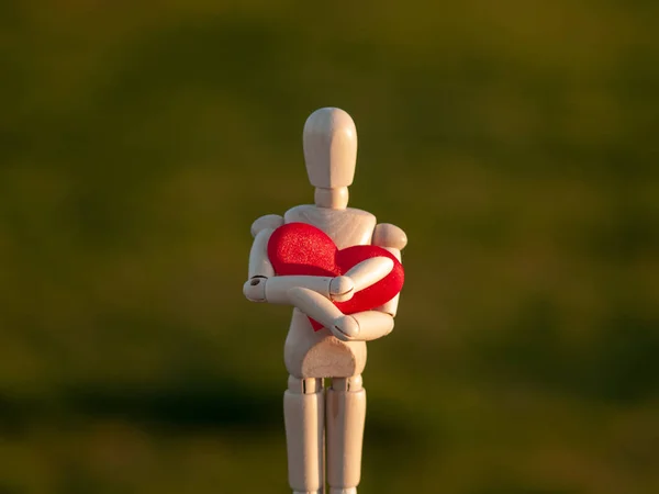 Деревянный манекен обнимает свое сердце руками Концепция романтизма и любви — стоковое фото