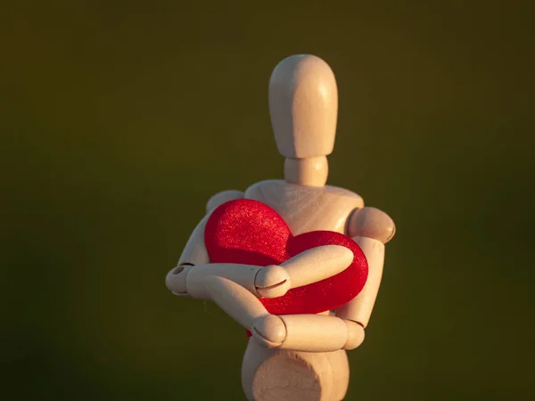 Schaufensterpuppe aus Holz umarmt sein Herz mit seinen Händen Konzept der Romantik und Liebe — Stockfoto