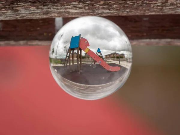 Reflexiones de columpios y toboganes en un parque en un concepto de bola de cristal / infancia —  Fotos de Stock