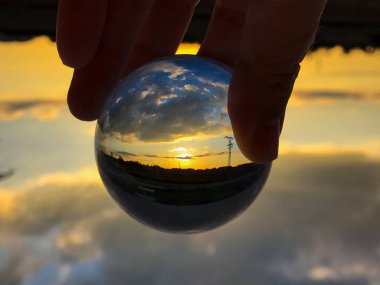 Bir kristal top bulutlu bir günde günbatımında yansımaları / çevre kavramı