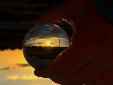 Bir kristal top bulutlu bir günde günbatımında yansımaları / çevre kavramı
