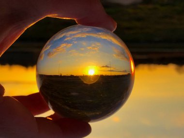 Bir kristal top bulutlu bir günde günbatımında yansımaları / çevre kavramı