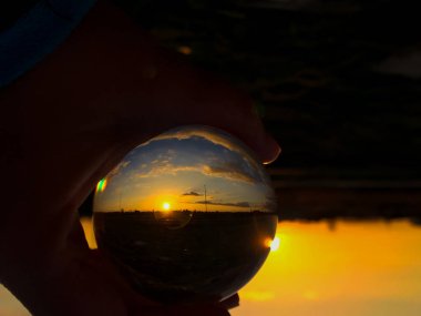 Bir kristal top bulutlu bir günde günbatımında yansımaları / çevre kavramı