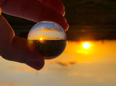 Bir kristal top bulutlu bir günde günbatımında yansımaları / çevre kavramı
