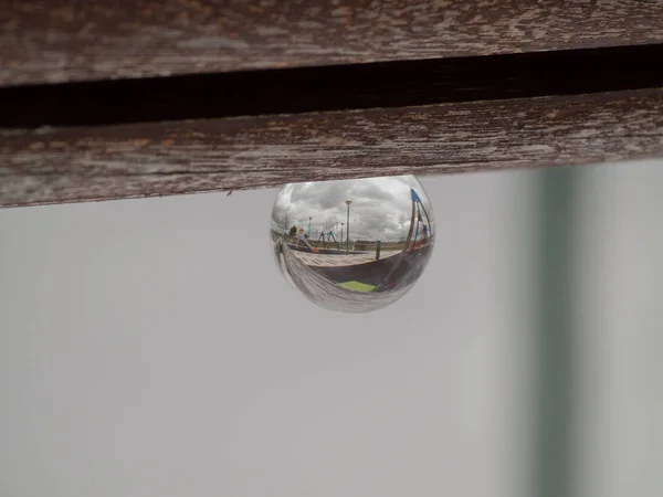 Reflexiones de columpios y toboganes en un parque en un concepto de bola de cristal / infancia — Foto de Stock