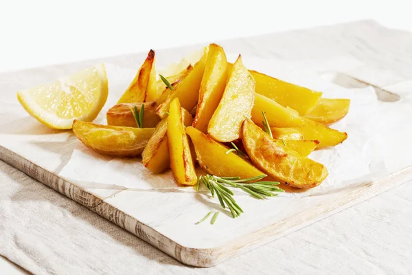 Zelfgebakken aardappelfrietjes met rozemarijn op wit houten bord — Stockfoto