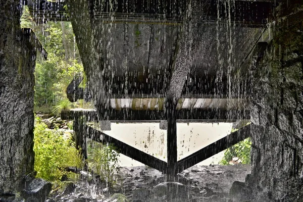 Dripping stream of water at the end of tunnel where is a wooden construction — Stock Photo, Image