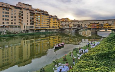 Gün batımında Ponte Vecchio köprüsü altında bahçe partisi