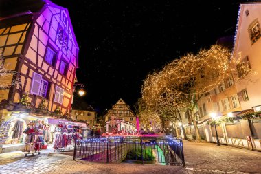 Colmar, Fransa - Aralık 1,2019: Fransa 'nın Alsace bölgesindeki Colmar şehrindeki geleneksel yarı keresteli evler arasında Noel Pazarı