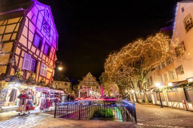 Colmar, Fransa - Aralık 1,2019: Fransa 'nın Alsace bölgesindeki Colmar şehrindeki geleneksel yarı keresteli evler arasında Noel Pazarı