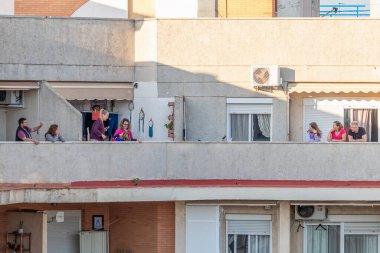 Huelva, Spain - April 5, 2020: Citizens staying at home and going out to the balconies everyday at 8 PM for clapping during the epidemic period of deadly coronavirus. People in quarantine in Spain clipart