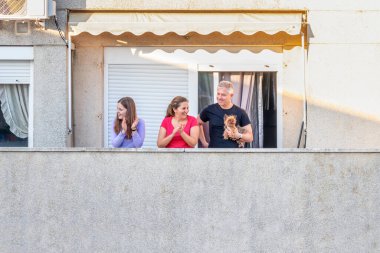 Huelva, İspanya - 7 Nisan 2020: Vatandaşlar ölümcül koronavirüs salgını sırasında her gün saat 8 'de evlerinde balkonlarda alkışlıyorlar. İspanya 'da karantinadaki insanlar