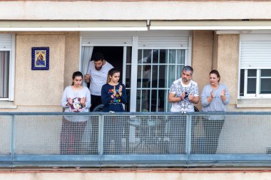 Huelva, İspanya - 7 Nisan 2020: Vatandaşlar ölümcül koronavirüs salgını sırasında her gün saat 8 'de evlerinde balkonlarda alkışlıyorlar. İspanya 'da karantinadaki insanlar