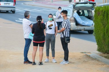 Huelva, İspanya - 6 Mayıs 2020: İspanya 'da alarm durumunda koruyucu maskeler takmış bir grup insan sohbet ediyor.