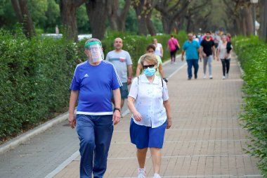 Huelva, İspanya - 6 Mayıs 2020: İspanya 'da alarm durumu ve karantinada şeffaf plastik miğfer takmış bir çift yürüyüşe çıkıyor.