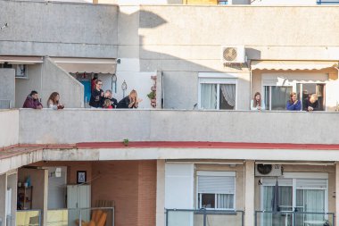 Huelva, İspanya - 27 Nisan 2020: Vatandaşlar ölümcül koronavirüs salgını sırasında her gün saat 8 'de evlerinde balkonlarda alkışlıyorlar. İspanya 'da karantinadaki insanlar