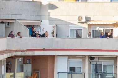Huelva, Spain - April 27,2020: Citizens staying at home and clapping everyday on balconies  at 8 PM during the epidemic period of deadly coronavirus. People in quarantine in Spain clipart