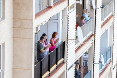 Huelva, İspanya - 10 Nisan 2020: Vatandaşlar ölümcül koronavirüs salgını sırasında her gün saat 8 'de evlerinde balkonlarda alkışlıyorlar. İspanya 'da karantinadaki insanlar