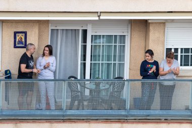 Huelva, İspanya - 10 Nisan 2020: Vatandaşlar ölümcül koronavirüs salgını sırasında her gün saat 8 'de evlerinde balkonlarda alkışlıyorlar. İspanya 'da karantinadaki insanlar