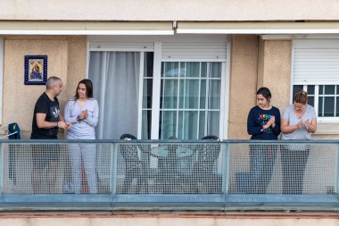 Huelva, Spain - April 10, 2020: Citizens staying at home and clapping everyday on balconies  at 8 PM during the epidemic period of deadly coronavirus. People in quarantine in Spain clipart