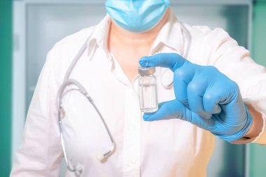 Laboratuvardaki bir doktor ya da bilim adamının elinde aşı şişesi.