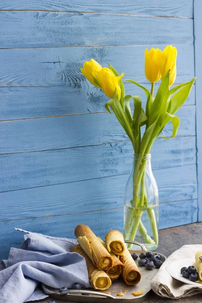 Hostienrollen und gelbe Tulpen in einer Glasvase — Stockfoto