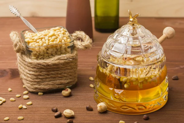 Un borcan de sticlă cu miere delicioasă cu nuci de pin. Banca cu nuci de pin — Fotografie, imagine de stoc