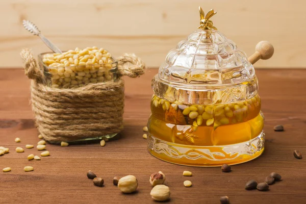 Un borcan de sticlă cu miere delicioasă cu nuci de pin. Banca cu nuci de pin — Fotografie, imagine de stoc