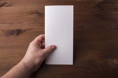 Boş üç katlı broşür tasarım veya mesaj ahşap arka plan üzerinde elinde.