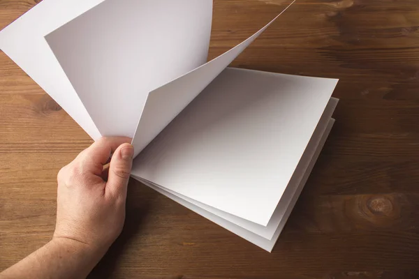 Leeg Witboek voor notities, notebook, dagboek, boekje, organisator in hand op een houten tafel. — Stockfoto