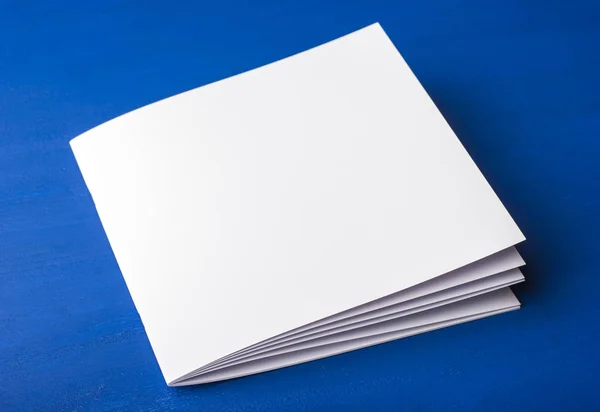 Prázdný dokument white paper pro poznámky, zápisník, diář, brožury, organizátor na modrém pozadí. — Stock fotografie