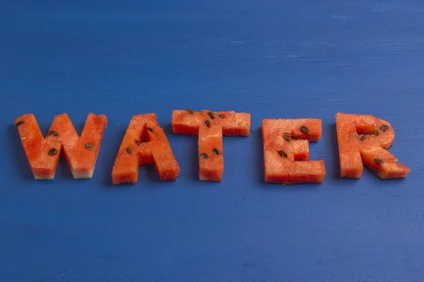 Het woord water is geschreven vanuit een segment van watermeloen met zaden — Stockfoto