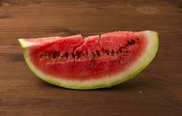 Plátek vodního melounu na dřevěné desce pozadí — Stock fotografie