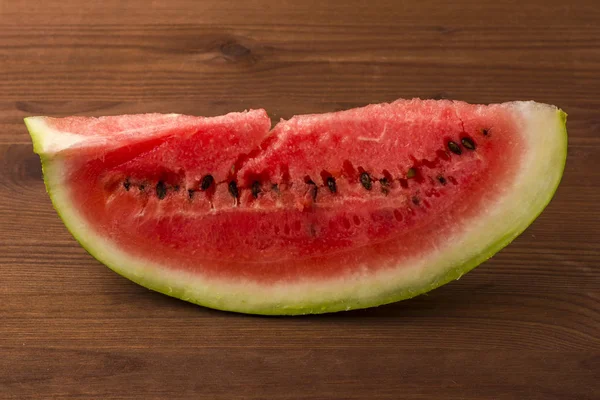 Plátek vodního melounu na dřevěné desce pozadí — Stock fotografie