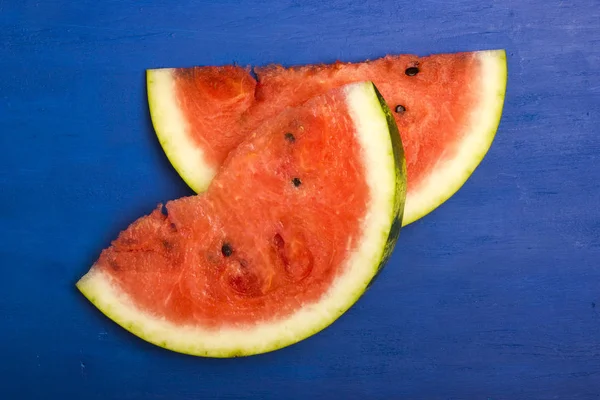 Dva kusy zralých, sladký meloun na dřevěné modré pozadí — Stock fotografie